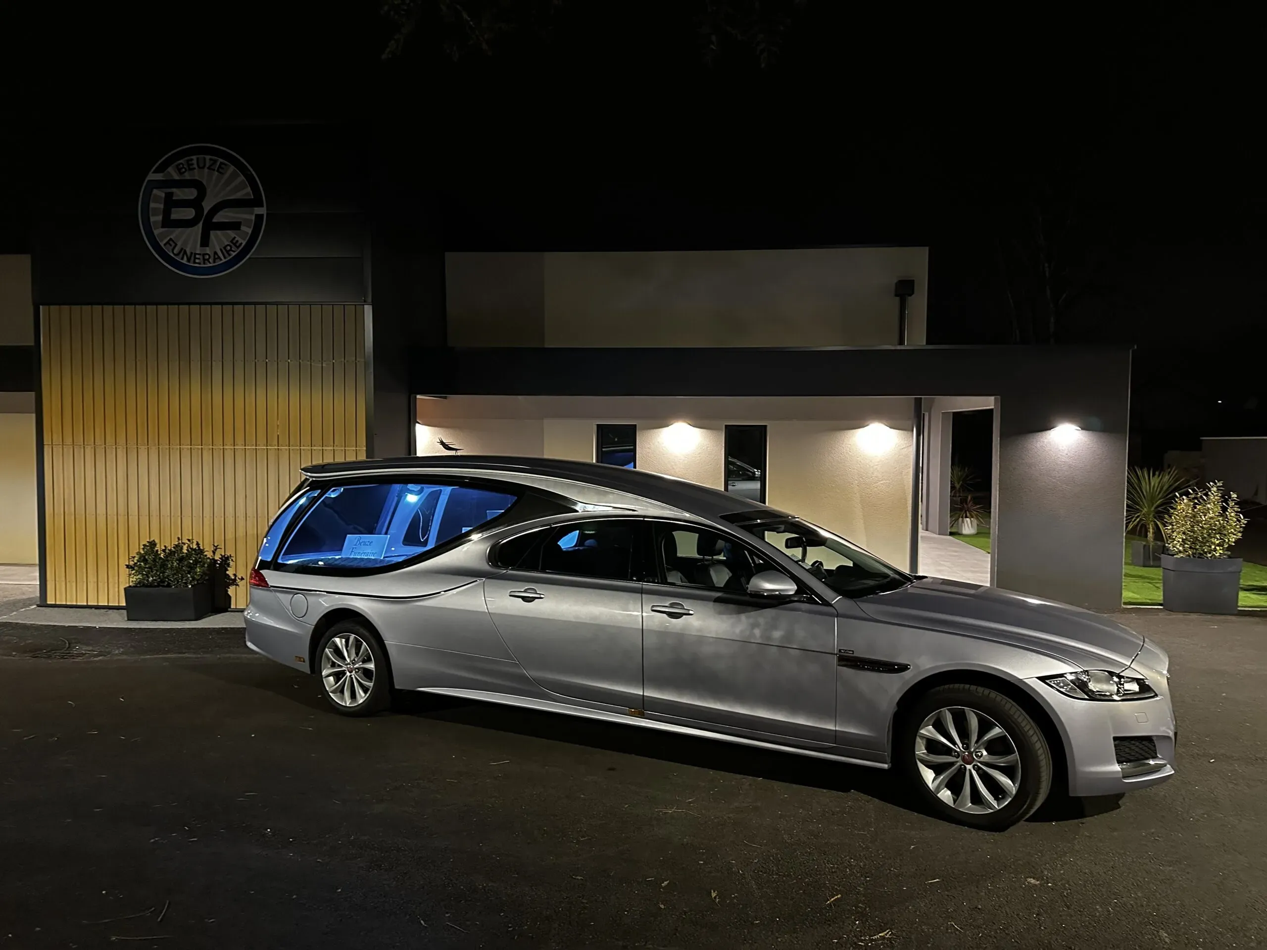 Corbillard de luxe gris garé de nuit devant la chambre funéraire Beuze.