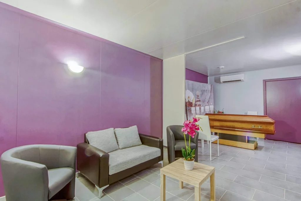 Salon de recueillement intimiste d'une chambre funéraire avec cercueil en bois.