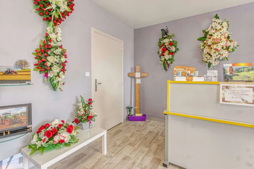 Espace d'accueil funéraire décoré de compositions florales et de plaques du souvenir.